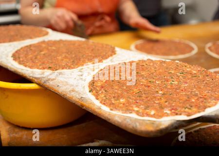 Une vue du processus de fabrication de manakish sur une surface de table en bois, dans un cadre de cuisine de restaurant. Banque D'Images