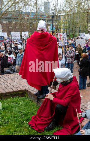 Seattle, Washington, États-Unis. 19 avril 2025. Les manifestants déguisés en personnages de « The Handmaid's Tale » se reposent lors du rassemblement et de la marche « We the People Means Everyone » au Seattle Central College de Seattle le samedi 19 avril 2025. La manifestation en faveur de la démocratie, de la diversité et de l’équité s’inscrit dans le cadre d’une journée nationale d’action contre les actions de l’administration Trump. Crédit : Paul Christian Gordon/Alamy Live News Banque D'Images
