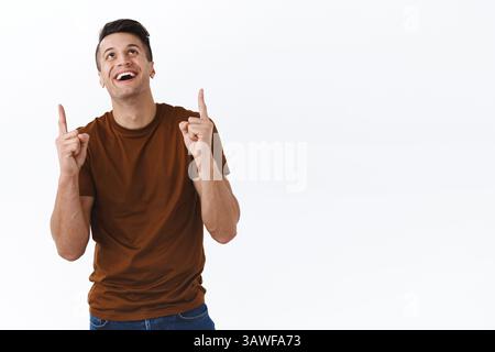 Portrait de joyeux, homme masculin caucasien heureux regardant et pointant les doigts vers le haut, montrant la publicité drôle, trouvé bonne affaire, appréciant la vue de SO Banque D'Images