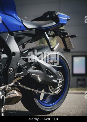 Gros plan d'une moto bleue sur la route avec un fort accent sur la chaîne Banque D'Images