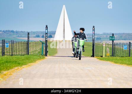 Les garçons s'éloignent de la pyramide légère de Milton Keynes. Cette œuvre d'art public se trouve au sommet du monticule ou belvédère, le point culminant du parc, où elle agit comme un phare à des kilomètres autour. Il a été allumé pour la première fois pour le jubilé de diamant de la Reine ElizabethÕs en 2012 et est toujours utilisé pour commémorer des événements locaux et nationaux spéciaux. Fondée dans les années 1960, Milton Keynes dans le Buckinghamshire était l'une des « nouvelles villes » du Royaume-Uni de cette époque. Souvent ridiculisé pour son architecture moderne terne, ses myriades de ronds-points et ses vaches en béton notoires, c'est en fait un endroit plutôt agréable à vivre, rempli de nombreux parcs, promenades Banque D'Images