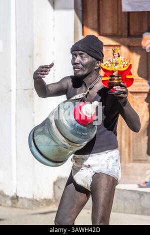 Participant masculin au Festival ATI-ATI à Aklan, Philippines portant un costume de bébé, tenant un grand biberon et une image du Sto.Nino Banque D'Images