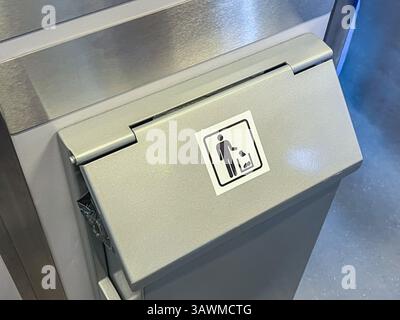 Vue rapprochée d'une poubelle métallique avec un panneau d'élimination des déchets, située dans un environnement intérieur propre. Le symbole promeut une bonne gestion des déchets Banque D'Images