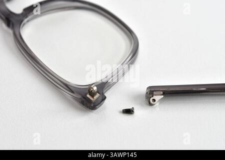 Vue rapprochée du bras cassé d'une paire de lunettes avec une petite vis à côté. Personne. Banque D'Images