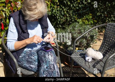 Femme âgée tricotant dehors dans le jardin Banque D'Images
