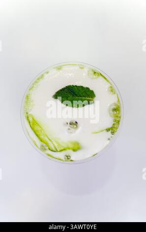 Un gros plan de haut en bas montre un verre transparent rempli d'un latte matcha vert éclatant, avec un art latte délicat dans la surface mousseuse et un seul vert Banque D'Images