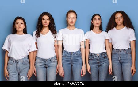 Groupe de femmes multiculturelles sérieuses posant sur fond bleu, Panorama Banque D'Images