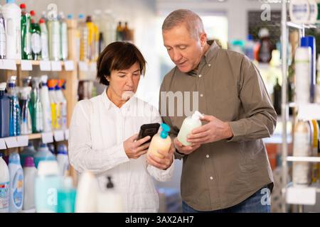 Couple homme et femme scannant le code qr pour le savon liquide Banque D'Images