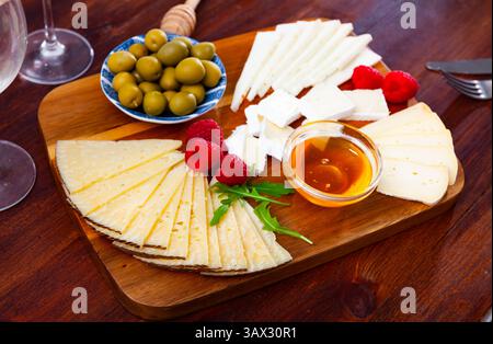 Différents types de fromage, miel, framboises et olives sur bois Banque D'Images