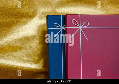 Cadeaux emballés avec des noeuds sur tissu doré. Coffrets cadeaux avec noeuds. Cadeaux emballés colorés sur fond d'or Banque D'Images