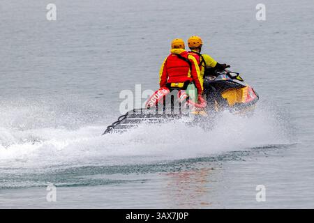 Deux membres de l'équipe de sauvetage naviguent à bord d'une motomarine personnelle sur une étendue d'eau tranquille par un après-midi couvert Banque D'Images