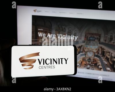 Dans cette illustration photo, une personne tient un smartphone avec le logo de la société immobilière australienne Neighborhood centres sur l'écran devant le site Web. Banque D'Images