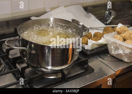 Chef frit des aliments dans une poêle flamboyante sur une table de cuisson à gaz dans une cuisine commerciale Banque D'Images