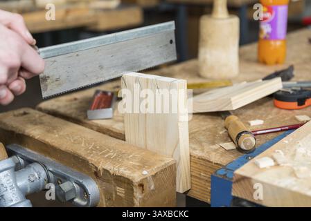 Menuisier avec une scie à main faisant des boiseries dans l'atelier - gros plan d'une scie à bois Banque D'Images