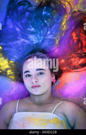 Femme couchée sur le sol avec des cheveux entourés de colo de poudre vibrante Banque D'Images