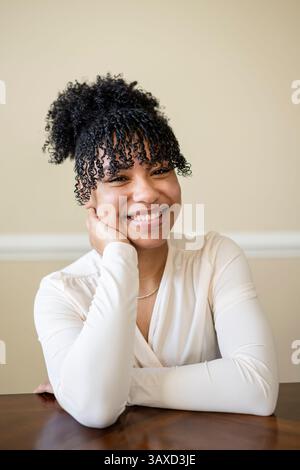 Femme appuyée sur la table souriante Banque D'Images