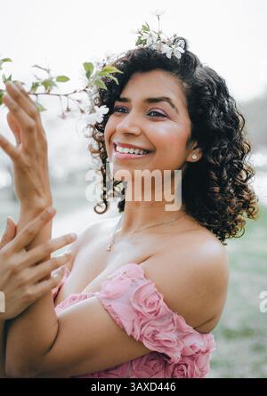 Une femme indienne sourit et touche la branche d'un cerisier en fleurs Banque D'Images
