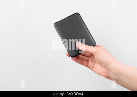 Homme avec disque dur externe sur fond gris clair, gros plan. Espace pour le texte Banque D'Images