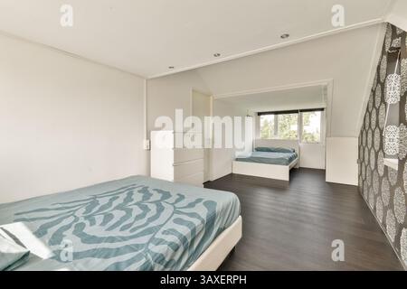 Cette chambre moderne spacieuse et lumineuse dispose de lits jumeaux, d'un décor minimaliste et d'un mobilier simple, créant une atmosphère sereine et accueillante. Banque D'Images