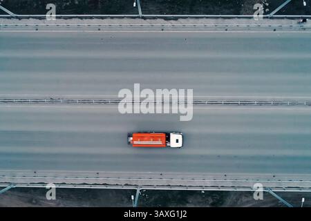 Un camion avec un réservoir de carburant orange traverse le pont. Banque D'Images