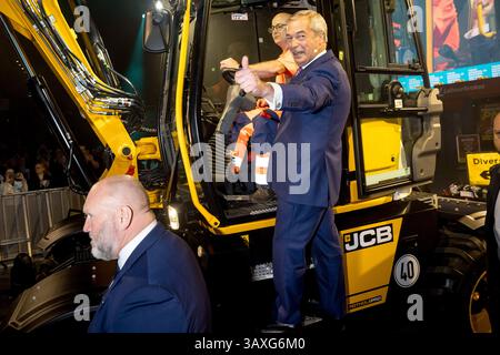 Nigel Farage, leader du Parti réformiste britannique et député de Clacton, arrive aux côtés d'un excavateur JCB avant de s'adresser à la foule lors du rassemblement de lancement de la campagne électorale locale et municipale de Reform partyÕs à l'Utilita Arena, Birmingham, Angleterre. Banque D'Images