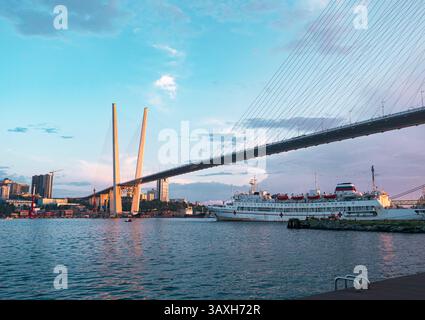 Vladivostok, Russie - 24 juin 2022 : vue du pont Zolotoy à Vladivostok avec des navires dans le port au coucher du soleil Banque D'Images