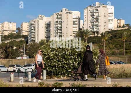 Haïfa, Israël, 16 avril 2025, Groupe diversifié marchant le long d'un trottoir dans un quartier résidentiel Banque D'Images