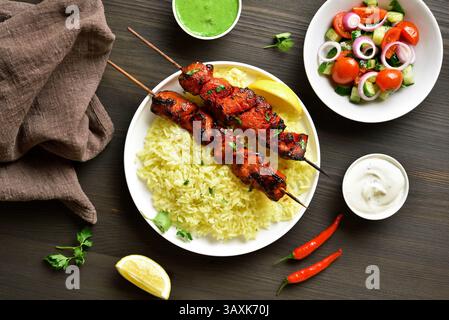 Poulet tandoori grillé cuit avec une savoureuse marinade à base de yaourt, aromatisée aux épices indiennes. Servi avec riz basmati. Fond en bois, haut Banque D'Images