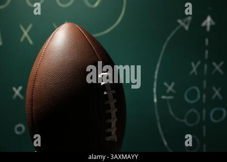 Ballon de football américain contre le schéma de jeu flou, gros plan Banque D'Images