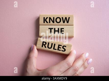 Connaître le symbole des règles. Les blocs de bois avec des mots connaissent les règles. Beau fond rose. Main d'homme d'affaires. Affaires et connaître le concept de règles. Copier Banque D'Images
