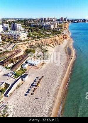 Vue aérienne de la côte de Mil Palmeras, montrant les maisons en bord de mer, promenade, plage de sable et mer Méditerranée turquoise sous ciel bleu clair Banque D'Images