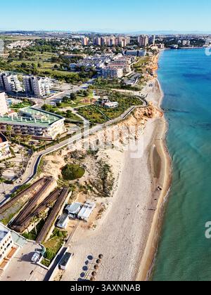 Vue aérienne de la côte de Mil Palmeras, montrant les maisons en bord de mer, promenade, plage de sable et mer Méditerranée turquoise sous ciel bleu clair Banque D'Images