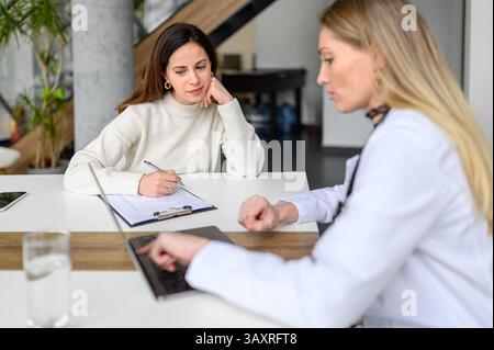 Patiente avec presse-papiers regardant la radiographie électronique sur ordinateur portable expliqué par le médecin lors de la consultation Banque D'Images
