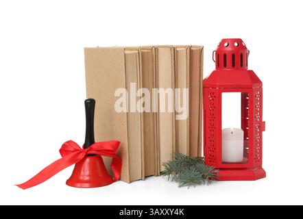 Ensemble de livres, lanterne avec bougie allumée et cloche de Noël sur fond blanc Banque D'Images