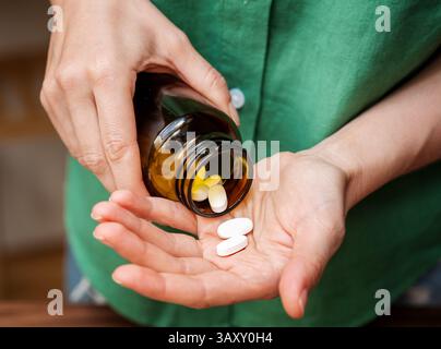 Femme versant des pilules de la bouteille dans sa main Banque D'Images