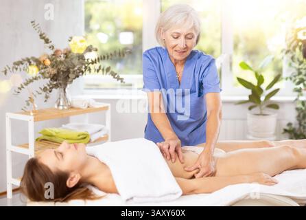 Masseuse mature qualifiée faisant des côtés anti-cellulite et massage du ventre à la femme Banque D'Images