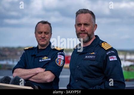 Le Commodore James Blackmore RN, commandant du Carrier Strike Group, à gauche, regarde le capitaine Will Blackett RN, commandant du HMS Prince of Wales, s’entretient avec les médias à bord du HMS Prince of Wales amarré à la base navale HM Portsmouth, alors qu’ils préparent le porte-avions devant lui à être déployé dans le cadre du UK Carrier Strike Group pour mener une formation à l’interopérabilité et un engagement de défense dans l’Indo-Pacifique. Date de la photo : mercredi 16 avril 2025. Banque D'Images