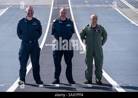 Le Capitaine Will Blackett RN, commandant du HMS Prince of Wales, à gauche, le Commodore James Blackmore RN, commandant du Carrier Strike Group, au centre, et le Capitaine Colin McGannity RN, commandant Air Group, à droite, à bord du HMS Prince of Wales amarré à la base navale HM Portsmouth, alors qu’ils préparent le porte-avions devant lui à être déployé dans le cadre du UK Carrier Strike Group pour mener une formation sur l’interopérabilité et un engagement de défense dans l’Indo-Pacifique. Date de la photo : mercredi 16 avril 2025. Banque D'Images