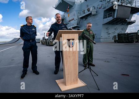 Le capitaine Will Blackett RN, commandant du HMS Prince of Wales, centre, rejoint par le commodore James Blackmore RN, commandant du Carrier Strike Group, à gauche, et le capitaine Colin McGannity RN, commandant Air Group, à droite, alors qu’ils répondent aux questions des médias à bord du HMS Prince of Wales amarré à HM Naval base Portsmouth, alors qu’ils préparent le porte-avions avant son déploiement dans le cadre du UK Carrier Strike Group pour mener une formation et un engagement de défense dans l’Indo-Pacifique. Date de la photo : mercredi 16 avril 2025. Banque D'Images