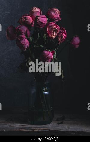 Bouquet séché roses roses dans un pot en verre sur fond sombre. Concept de relations Banque D'Images