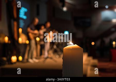 Culte de l'église, gros plan sur la bougie avec fond flou de musiciens. Banque D'Images