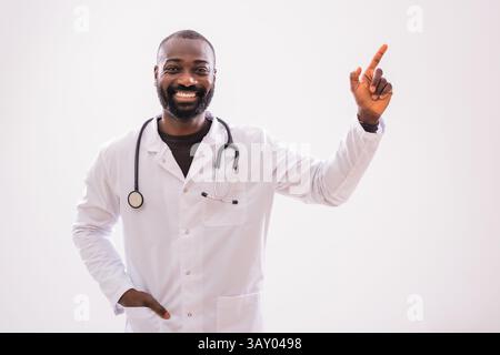 Portrait d'un médecin afro-américain qui pointe vers le haut avec un sourire joyeux. Espace de copie pour votre texte ou publicité. Banque D'Images
