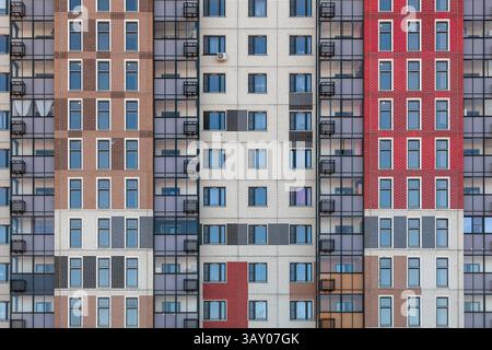 Un fragment du mur d'un bâtiment moderne de plusieurs étages avec des fenêtres et des balcons identiques. Banque D'Images