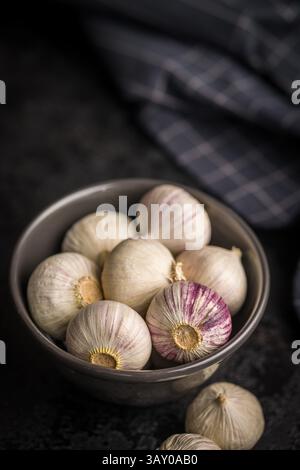 Bulbes d'ail gant solo dans un bol sur une table noire. Banque D'Images