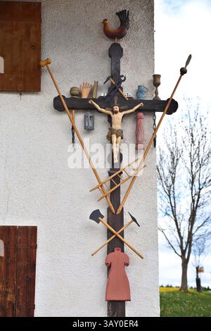 22 avril 2025, Bavière, Marktoberdorf : une croix d'Arma Christi est accrochée au mur d'une ferme. Sur une croix d'Arma Christi, des instruments de souffrance et des symboles de la crucifixion sont ajoutés à la figure de Jésus. Photo : Karl-Josef Hildenbrand/dpa Banque D'Images