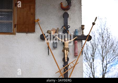22 avril 2025, Bavière, Marktoberdorf : une croix d'Arma Christi est accrochée au mur d'une ferme. Sur une croix d'Arma Christi, des instruments de souffrance et des symboles de la crucifixion sont ajoutés à la figure de Jésus. Photo : Karl-Josef Hildenbrand/dpa Banque D'Images