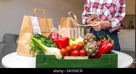 Service de livraison agricole de légumes frais biologiques. Personne féminine scannant le code QR sur la réception de la commande. Banque D'Images