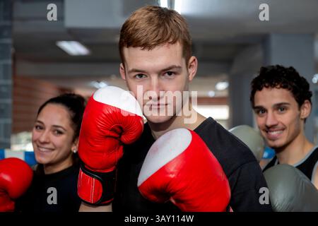 Groupe de jeunes boxeurs portant des gants de boxe posant dans un ring de boxe, prêts pour l'entraînement ou la compétition Banque D'Images