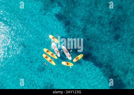 Vue aérienne de kayaks jaunes en mer bleue au coucher du soleil en été. Les gens sur des canoës flottants dans l'eau Azur claire. Île de Sardaigne, Italie. Landsca tropical Banque D'Images