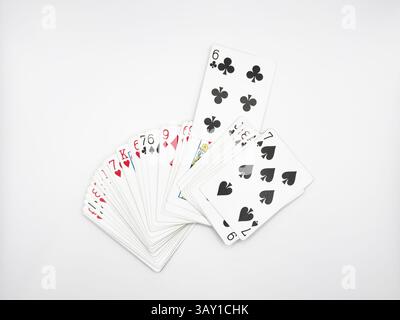 Les cartes de poker en plastique blanc se sont étendues au centre de l'image avec un six de trèfles allongés sur un fond blanc. Photo de haute qualité Banque D'Images